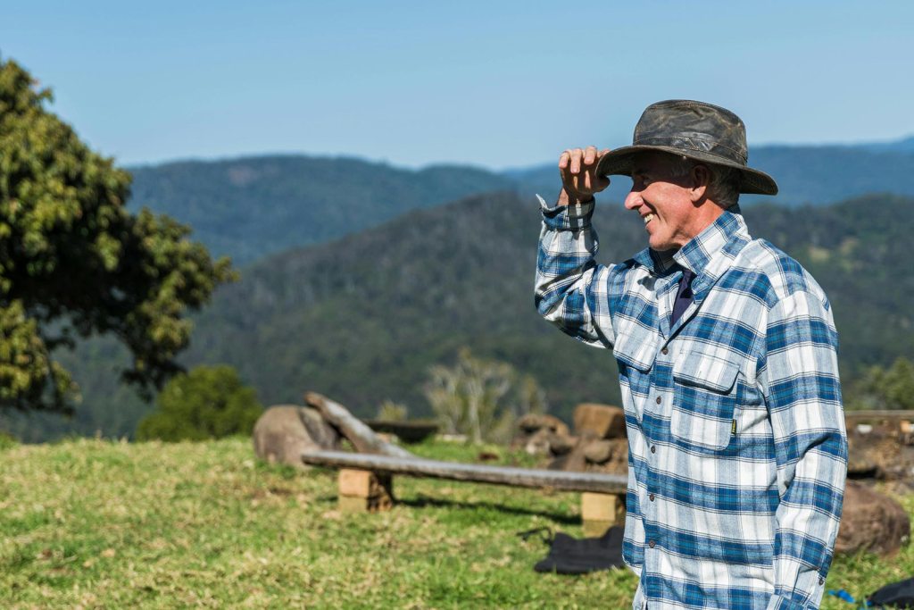 A farmer holds his hat on a windy day